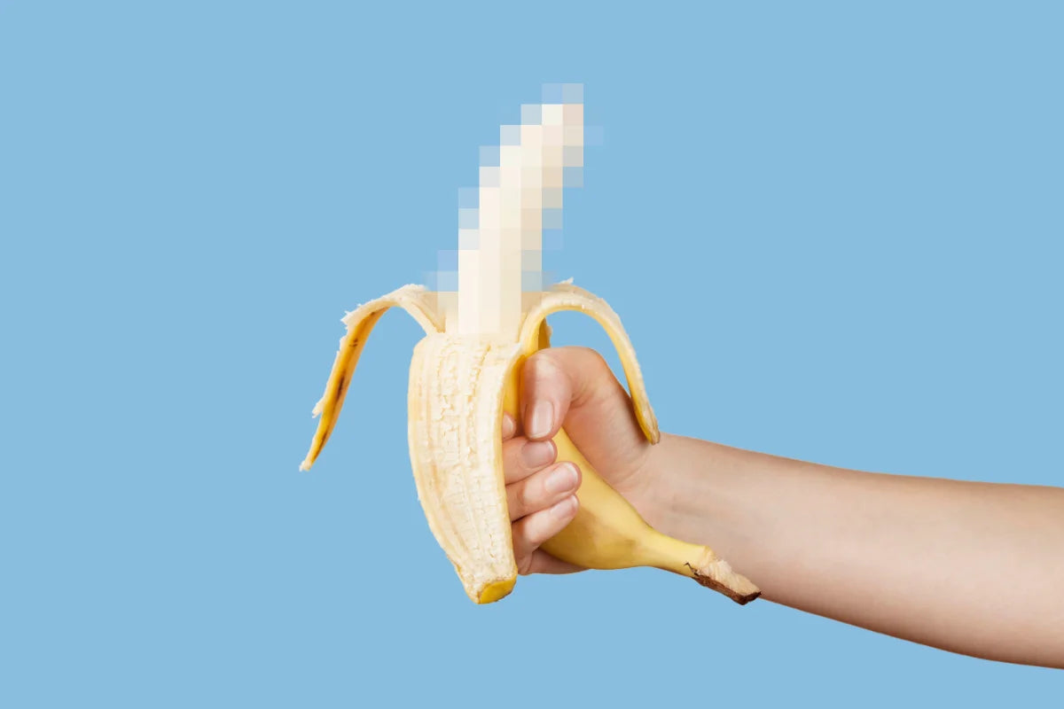 Hand holding a peeled banana against a blue background